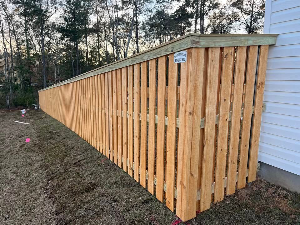 A wooden fence is sitting next to a white house.