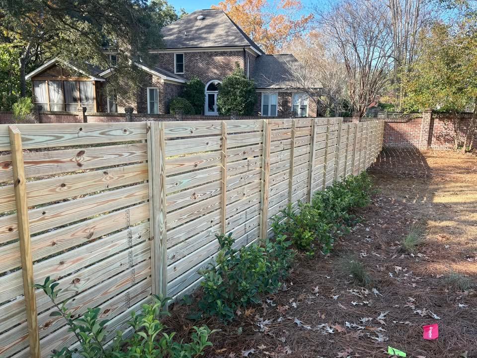 A wooden fence is in the backyard of a house.