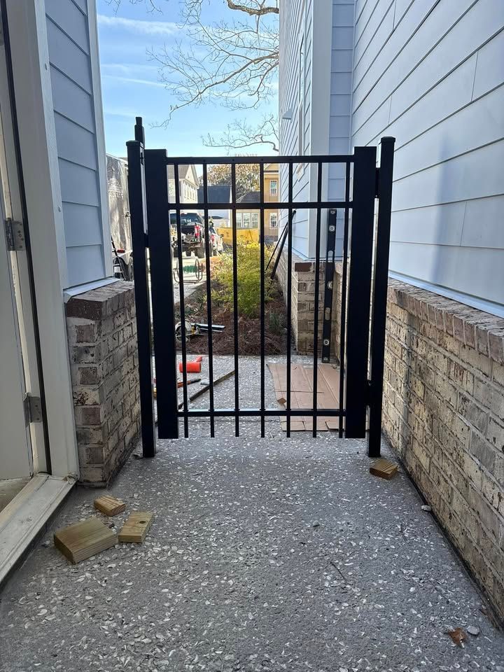 A black gate is sitting on the side of a building next to a brick wall.