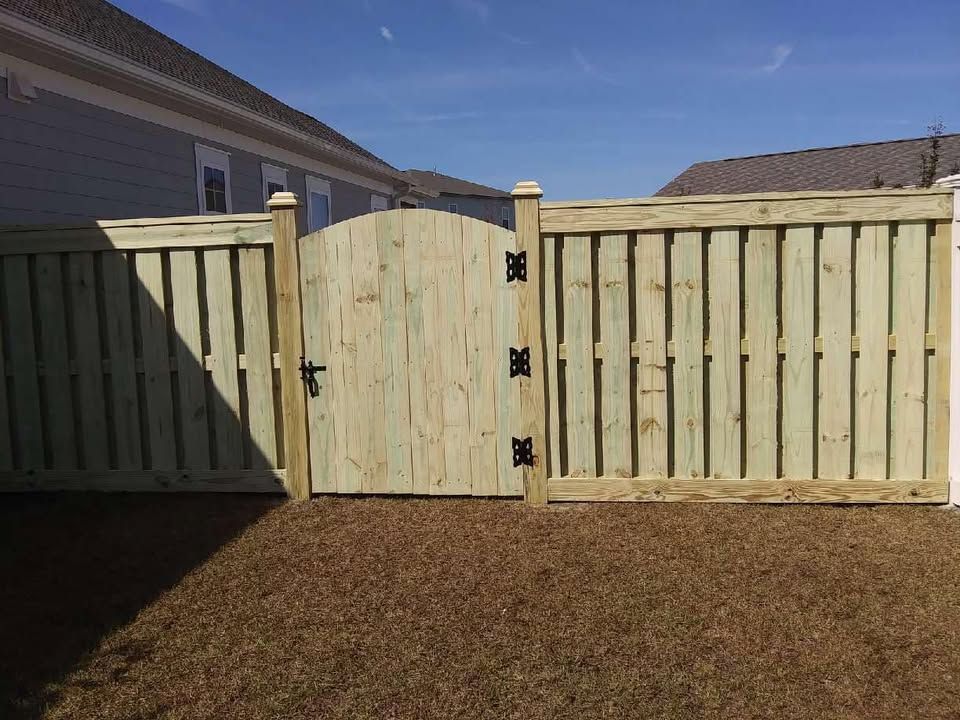 A wooden fence with a gate in the backyard of a house.