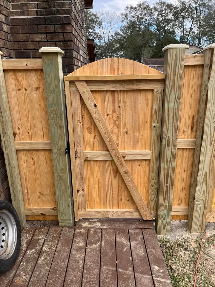 A wooden gate is sitting on top of a wooden deck next to a wooden fence.