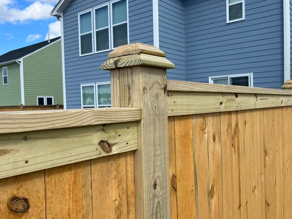 A wooden fence is in front of a blue house.