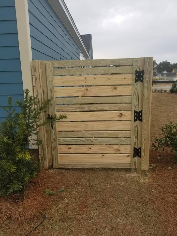 A wooden gate is sitting in front of a blue house.