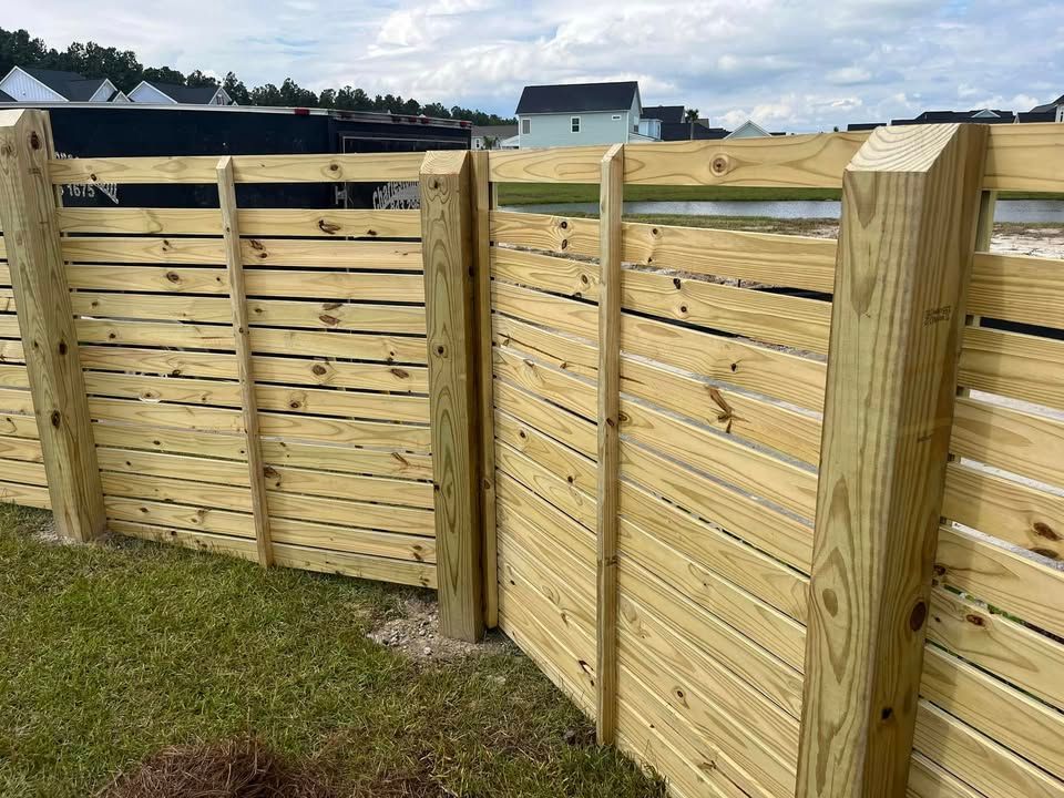 A wooden fence is sitting on top of a lush green field.