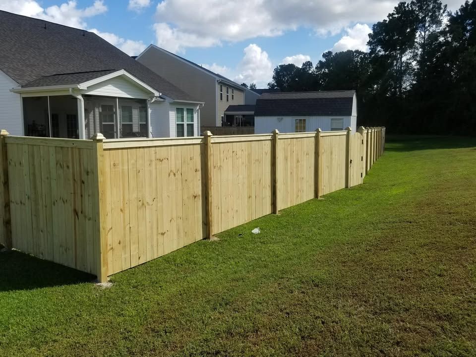 A wooden fence is in the backyard of a house.