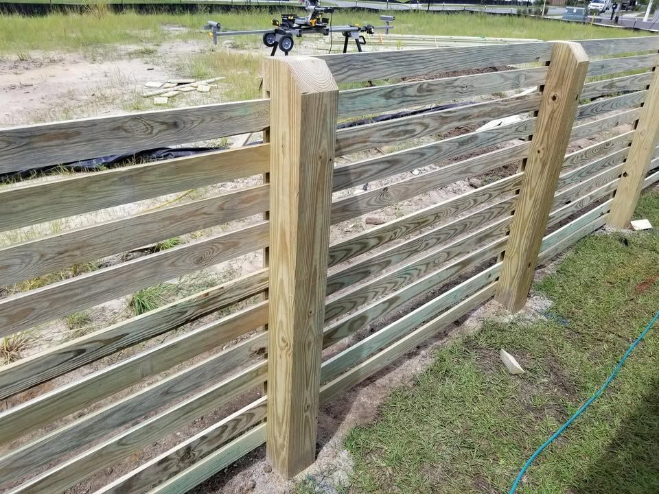 A wooden fence is being built in a yard.