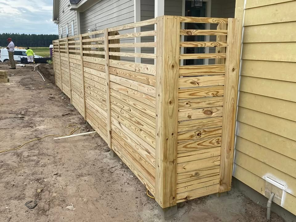 A wooden fence is being built on the side of a house.