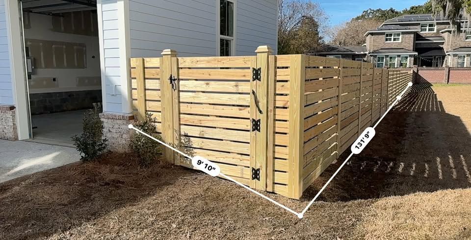 A wooden fence with a gate in front of a house.