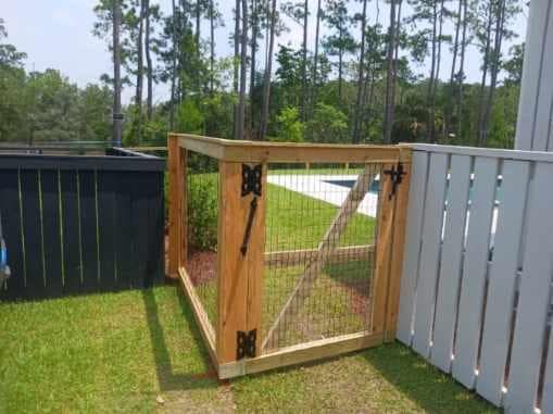 A wooden fence with a gate is sitting on top of a lush green lawn.