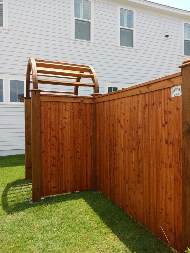 A wooden fence with a wooden arch in the backyard of a house.