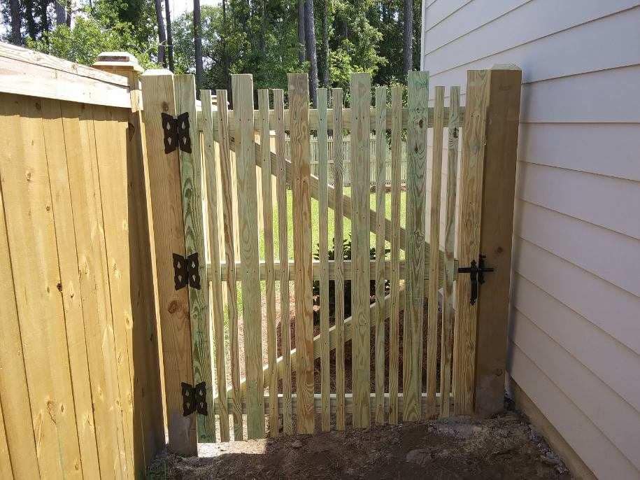 A wooden fence with a gate between it and a house