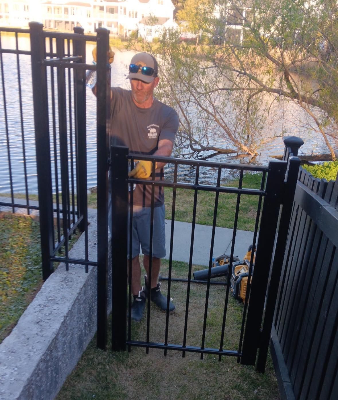 A man and a woman are standing next to a chain link fence with a dog behind them.