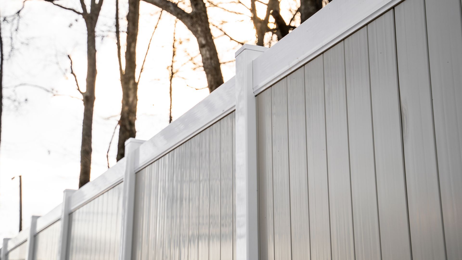 A white fence with trees in the background