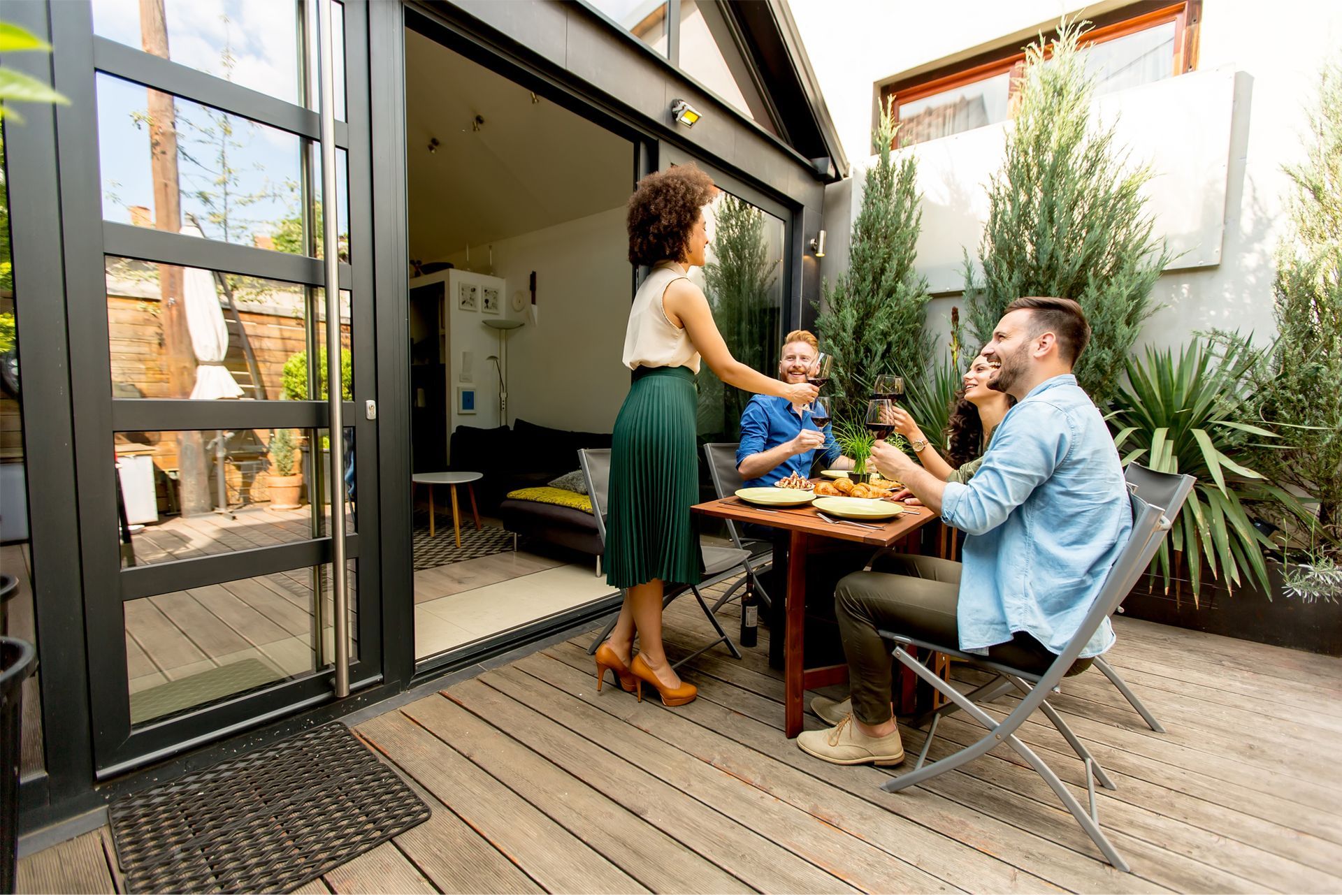 A family is sitting at a table on a deck eating food.