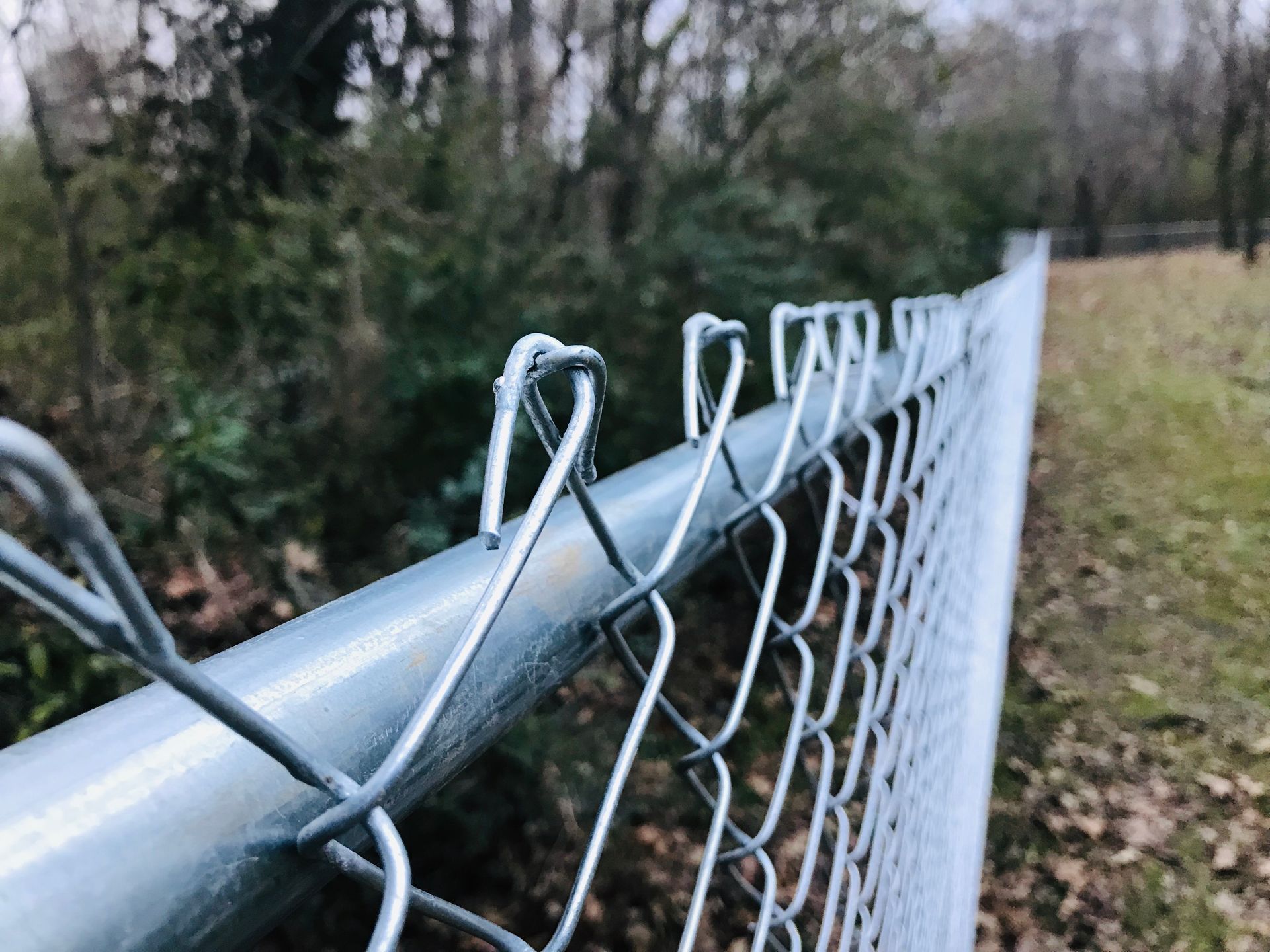 A close up of a chain link fence with trees in the background.