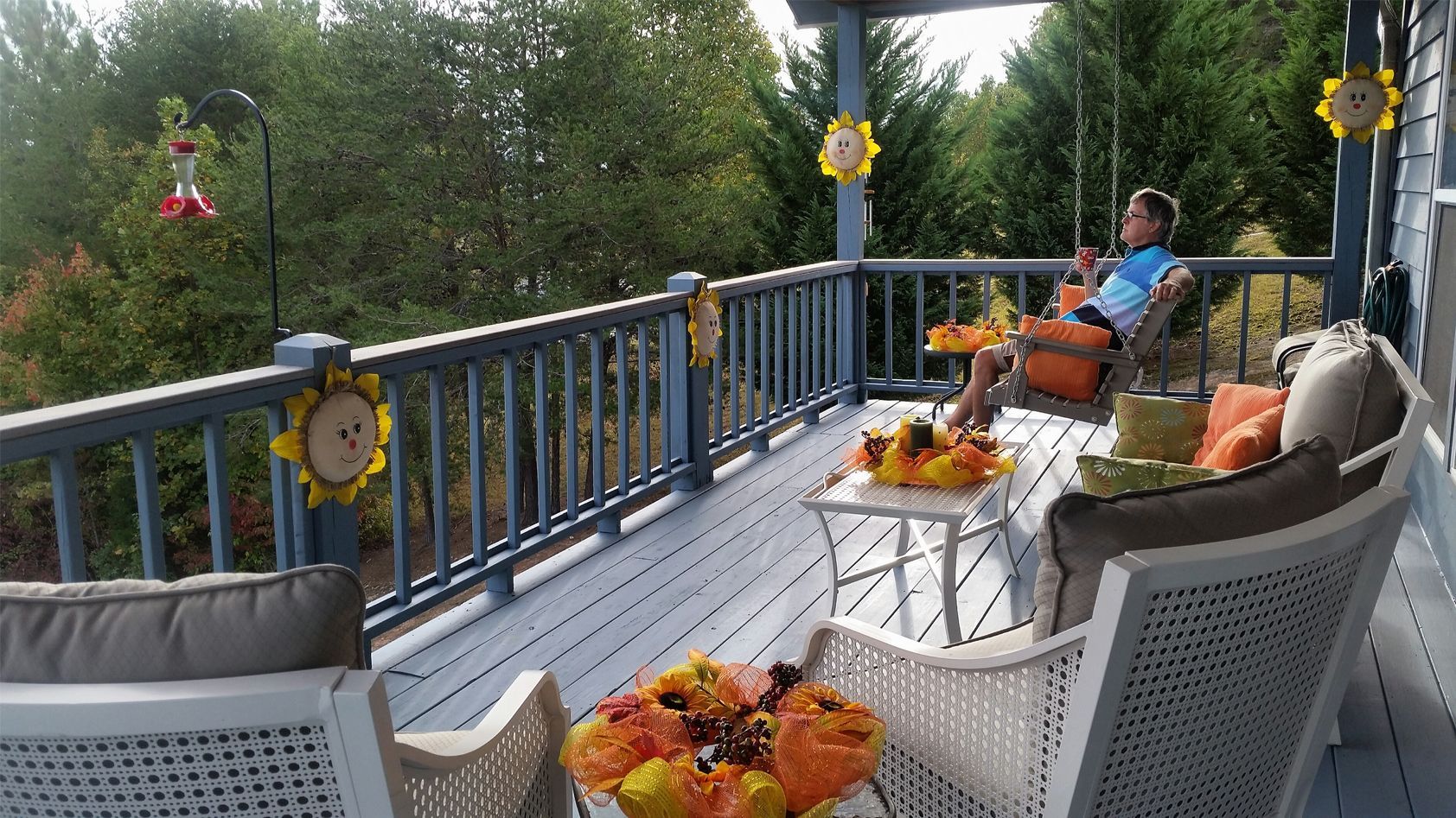 A woman is sitting on a porch with a swing.