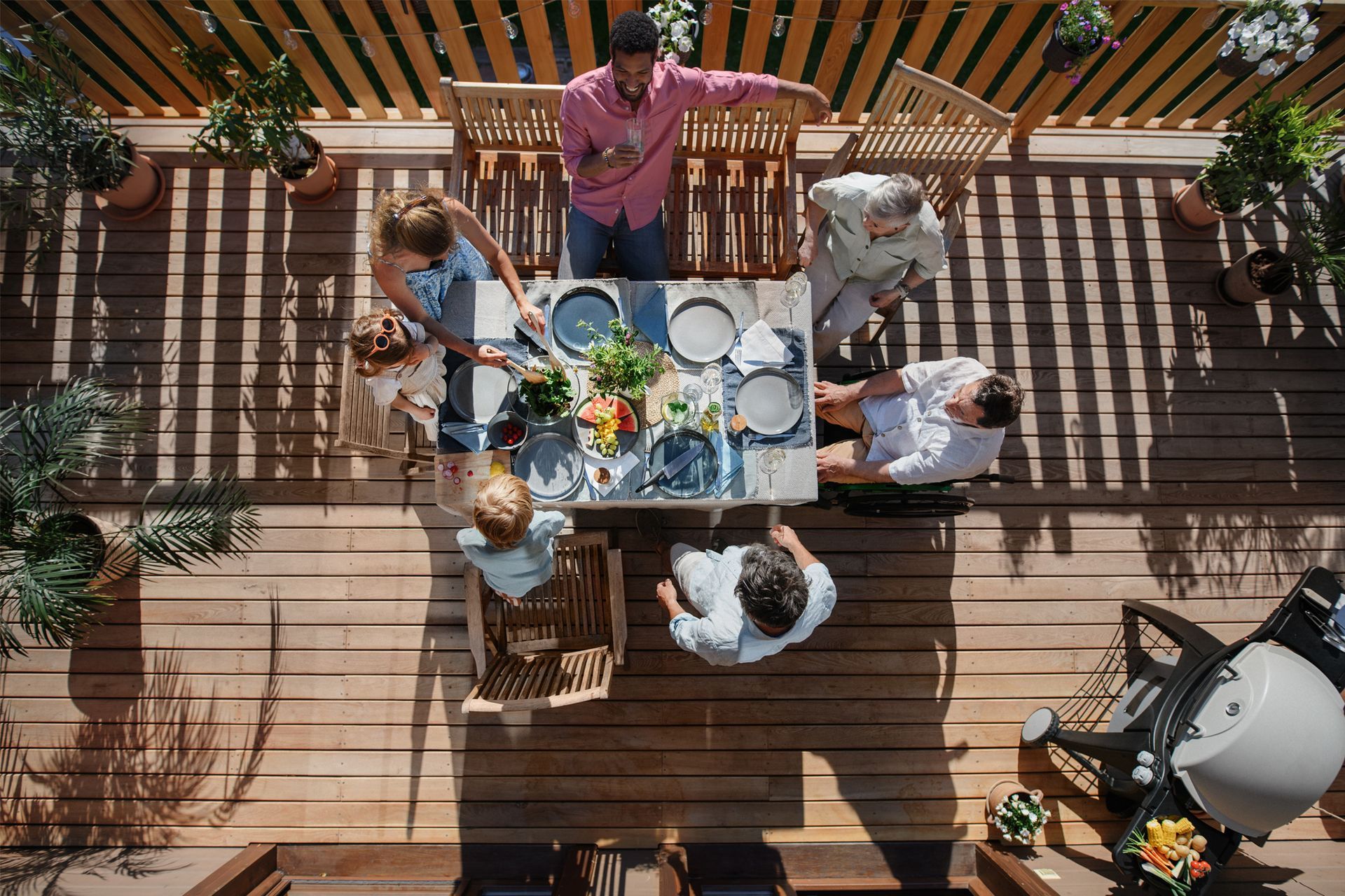 A group of people are sitting around a table on a deck.