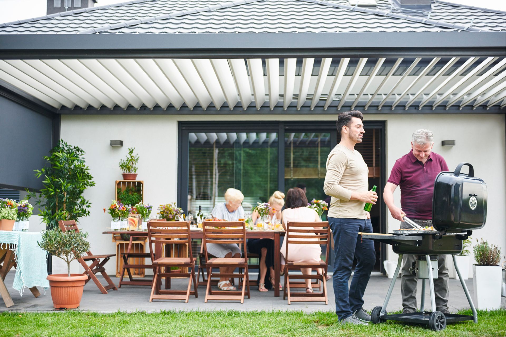 A group of people are having a barbecue in front of a house.