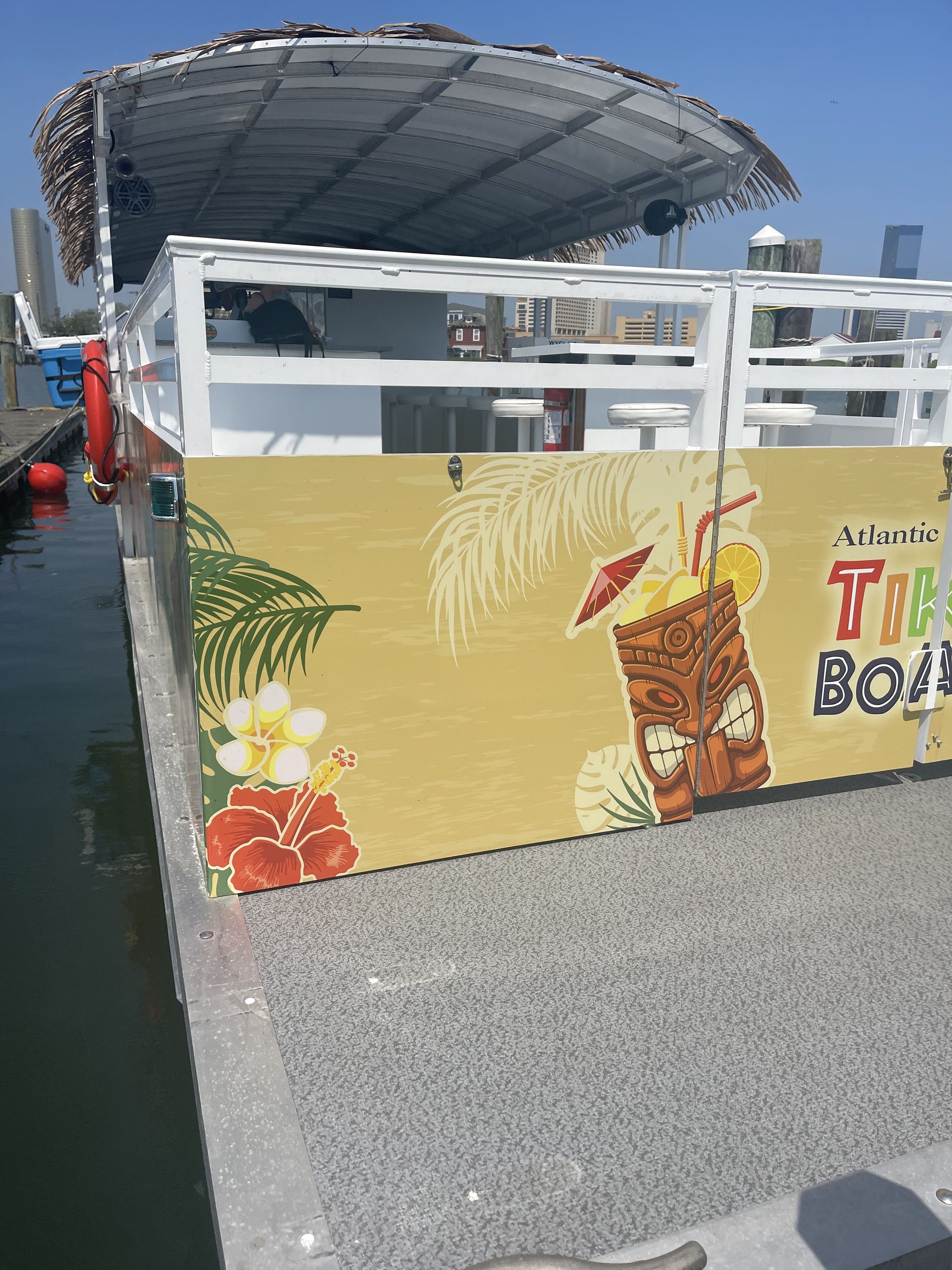 A Tiki Boat on the water with a yellow and brown mural featuring a tiki mask and tropical flowers.