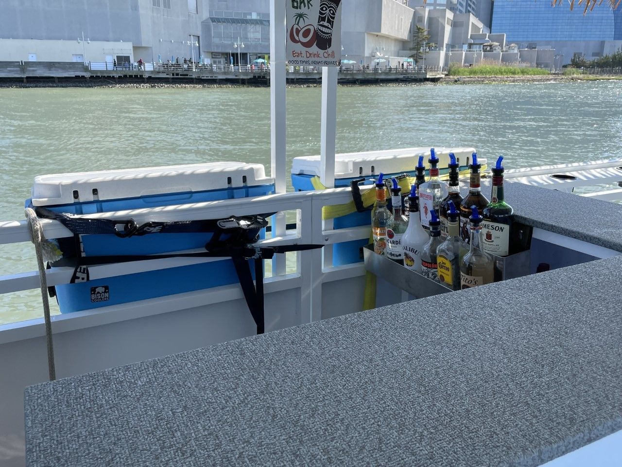 Boat bar with bottles, coolers, and the water in the background.