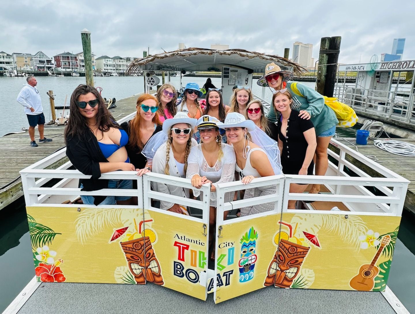 Group of women on a decorated tiki boat, posing for a photo at a dock.