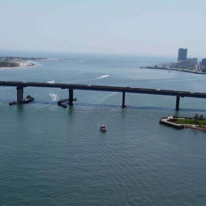 Bridge over water with boats, distant buildings, and a clear sky.