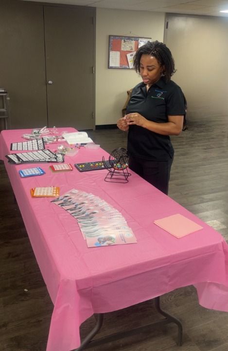 Woman stands behind a table with jewelry displayed on a pink tablecloth