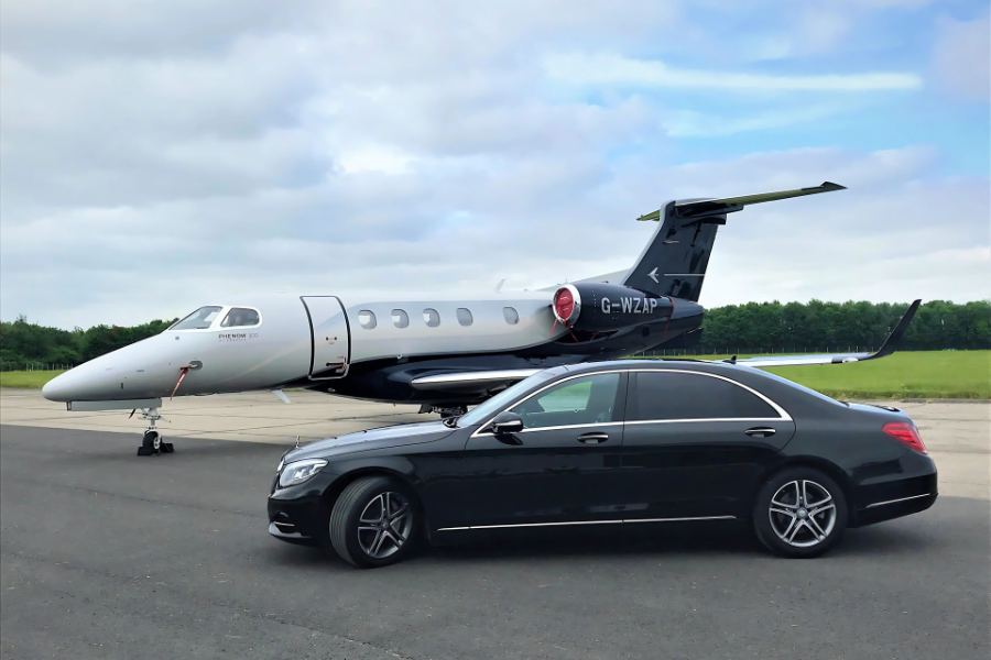 Athenaos Travel & Tours Mercedes E-Class sedan providing private executive transfer beside a private jet.