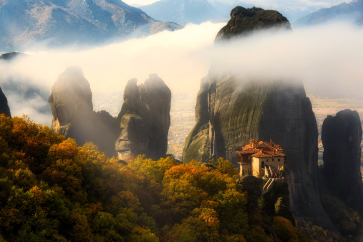 Meteora rock formations covered in mist with monastery view