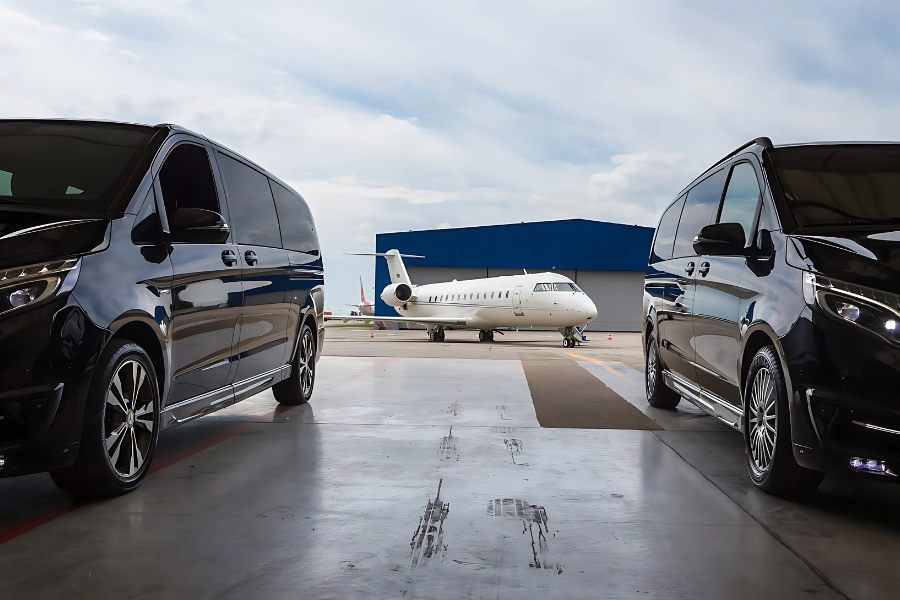 Athenaos Travel & Tours Mercedes luxury minivans parked at an airport hangar beside a private jet.