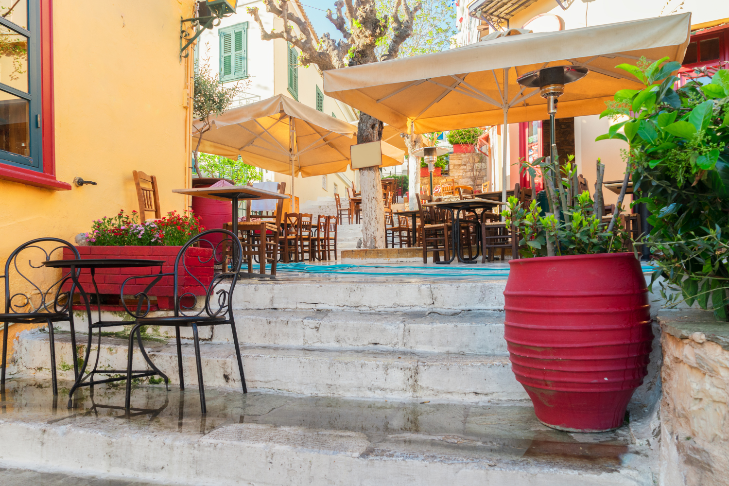 Café terrace in the Plaka neighborhood of Athens with colorful chairs and plants