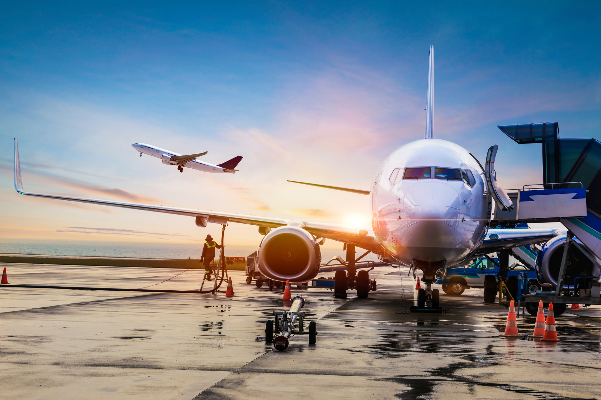 Commercial airplane at the airport gate during sunrise symbolizing domestic and international flights with Athenaos.