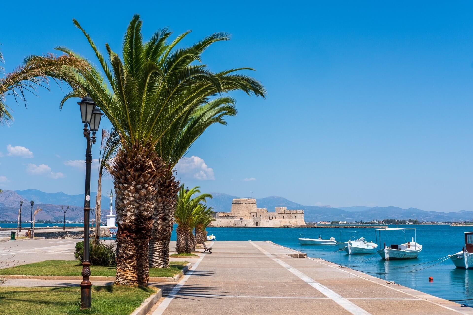 Seaside promenade in Nafplio with palm trees and Bourtzi fortress