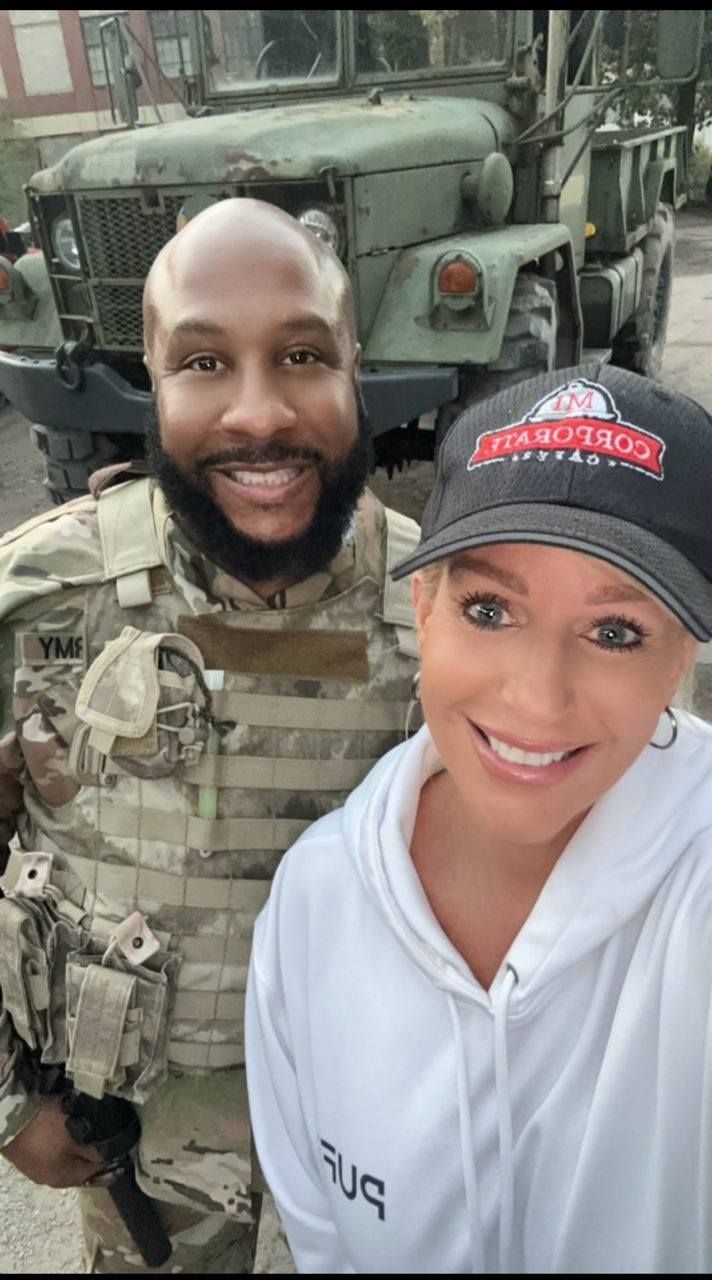 A man and a woman are posing for a picture in front of a military vehicle.