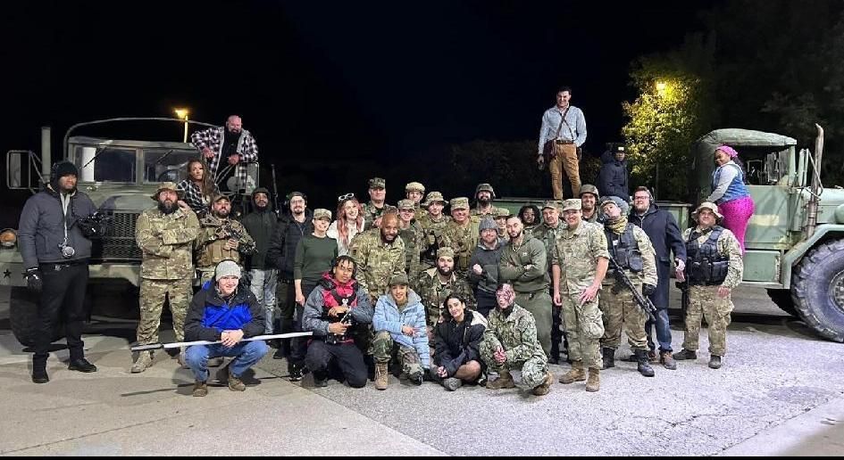 A group of soldiers are posing for a picture in front of military vehicles.