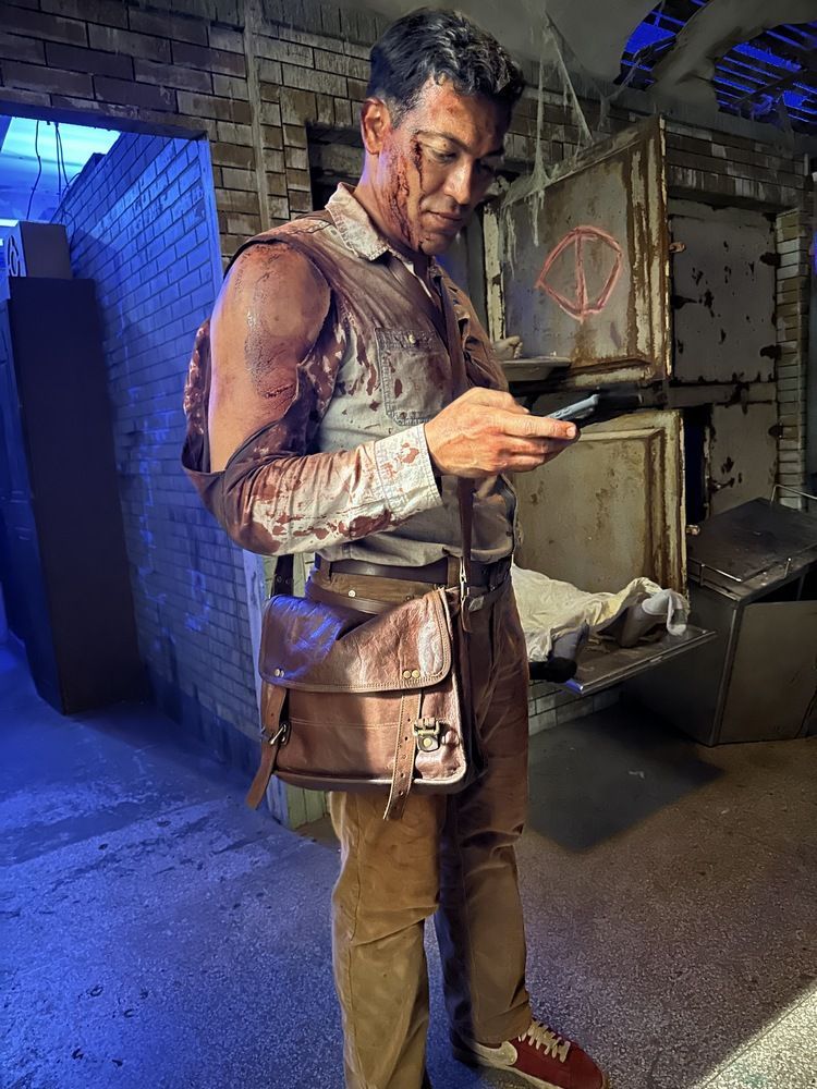 A man is standing in a dark room looking at his cell phone.