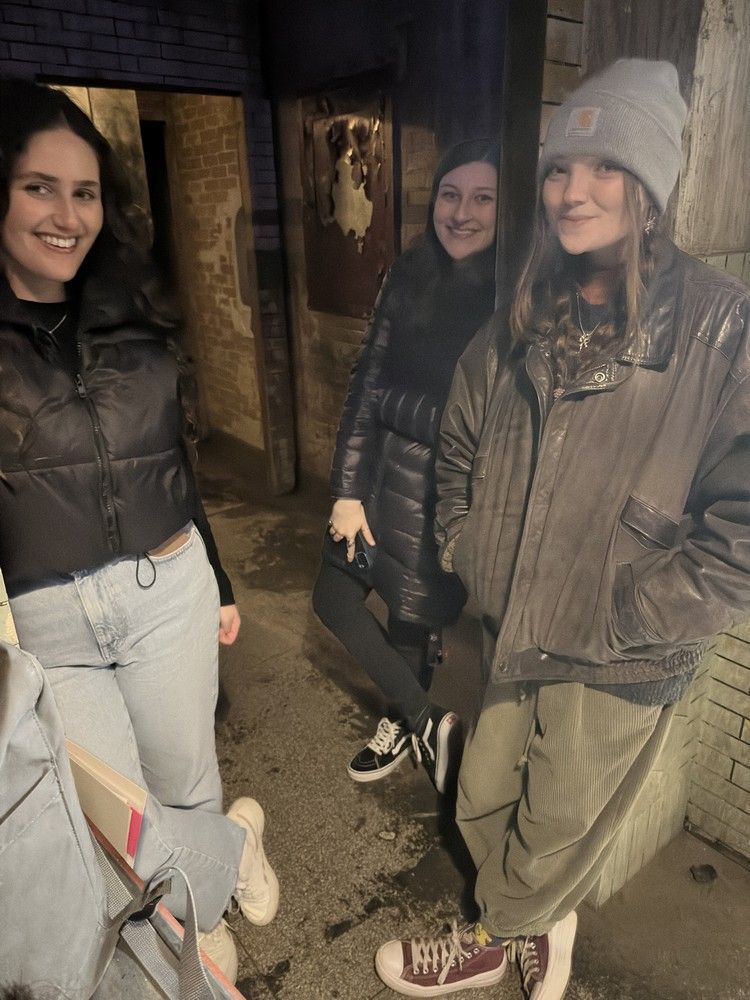 Three young women are standing next to each other on a sidewalk.