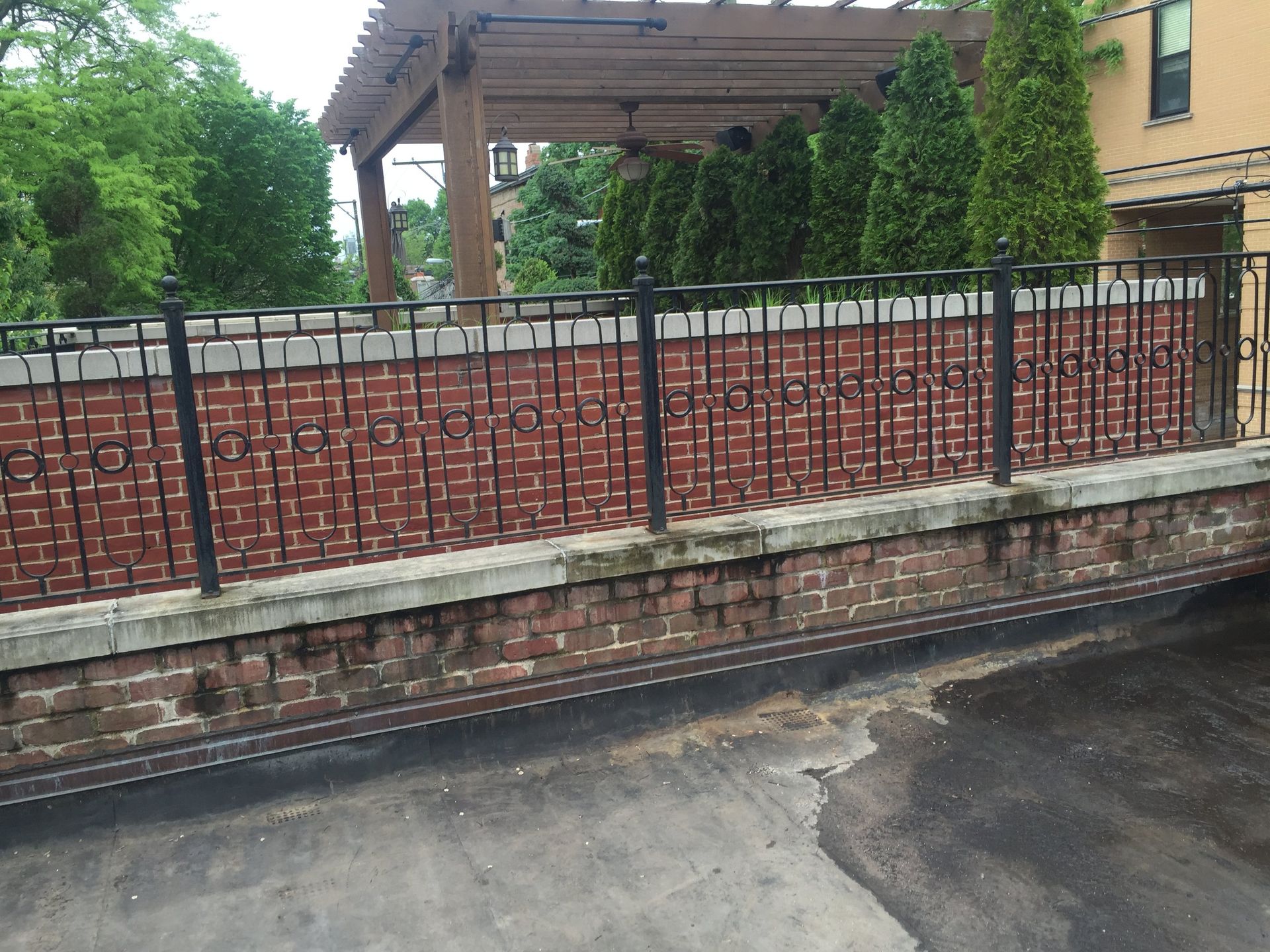 Iron railing on short wet brick parapet wall