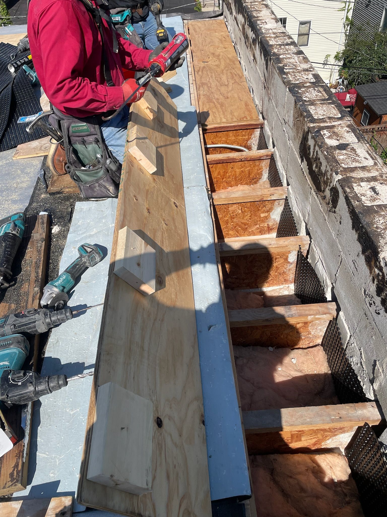 Worker installing plywood boards on top of trusses
