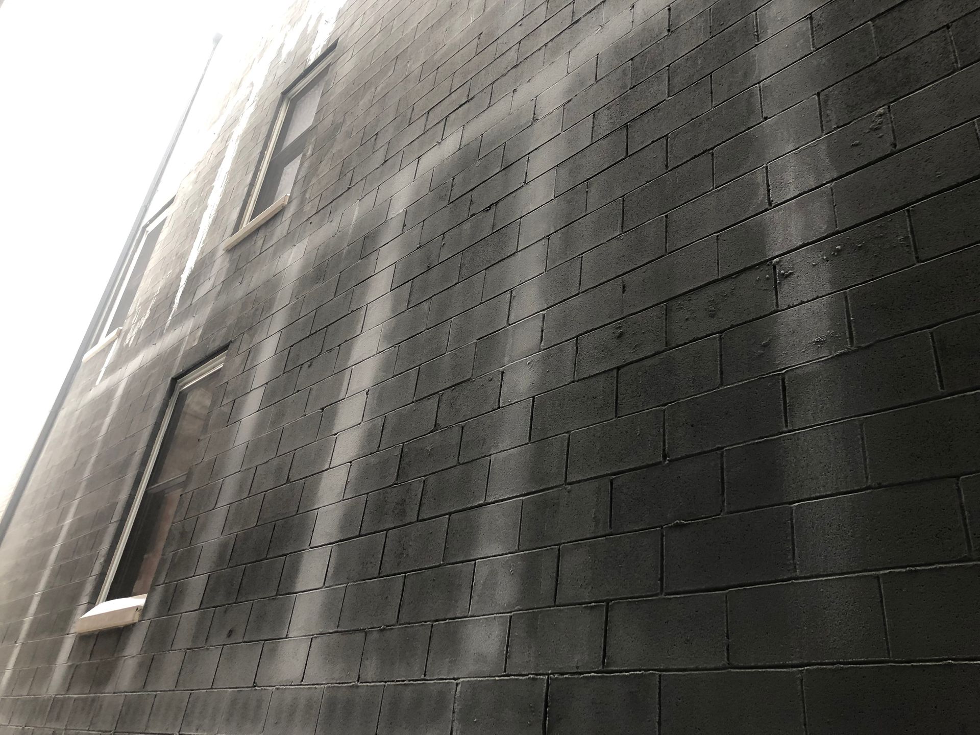 Concrete block building with dark gray elastomeric coating show water frozen in block cores, Little Village, Chicago, IL 