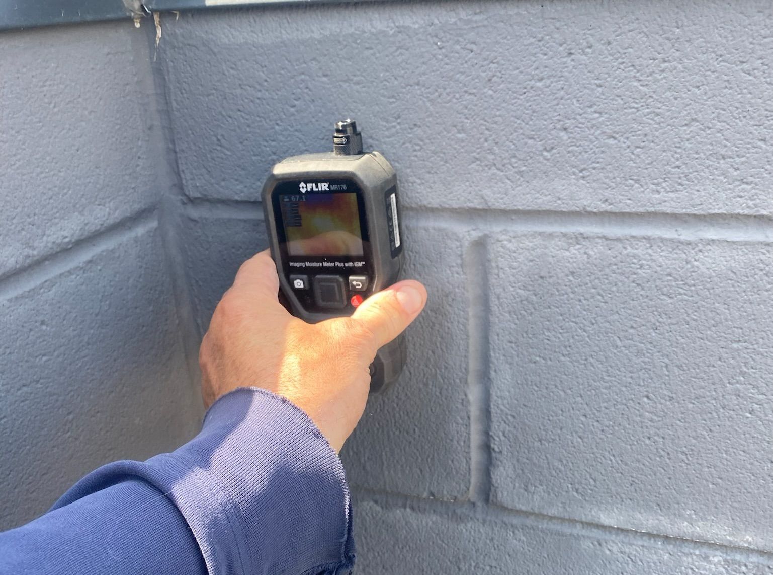 Moisture meter on wet cement block wall showing 85 percent moisture - average normal moisture content is 30 percent or less.