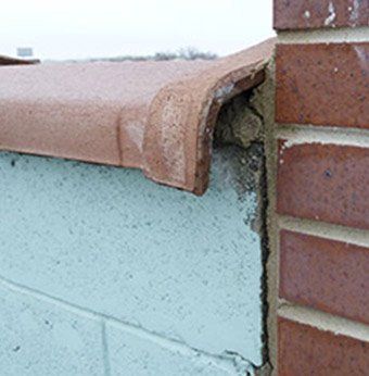 Oversized clay coping on concrete wall allows wind driven rain to enter parapet wall, Chicago