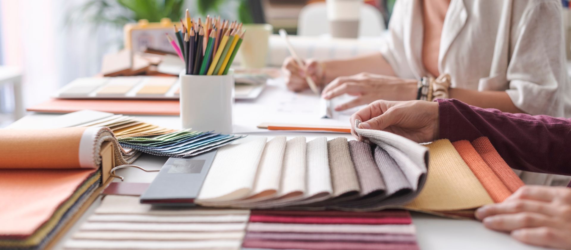 Interior decorators reviewing fabric swatches and color samples spread across a workspace.