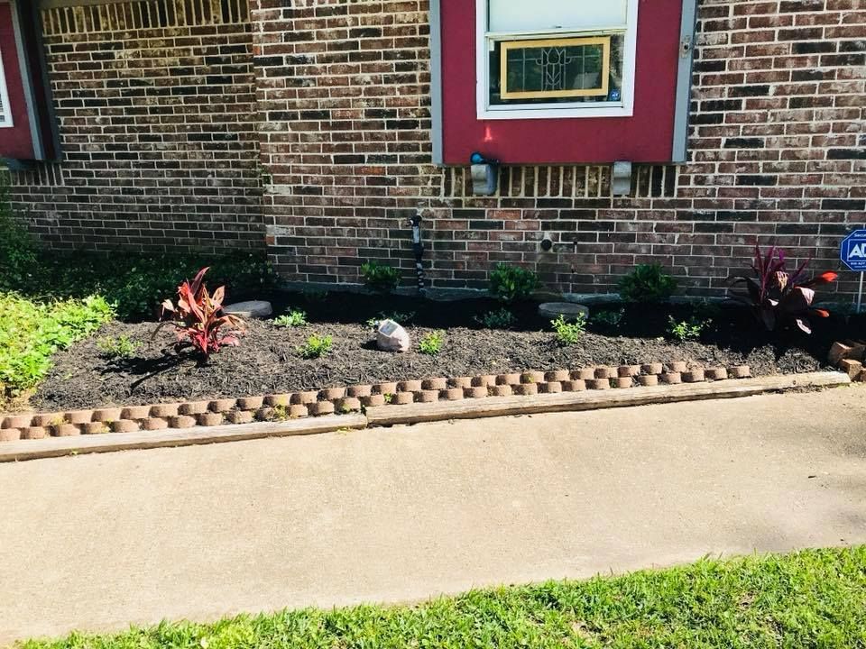 A garden with flowers and a bench in front of a fence