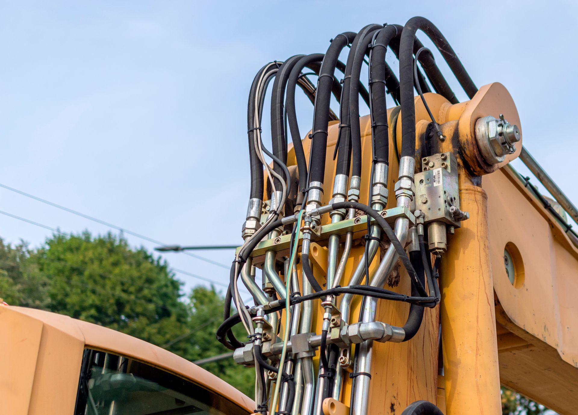 A close-up of an excavator with hydraulic pipes outdoors. A close-up of an excavator with hydraulic pipes outdoors.