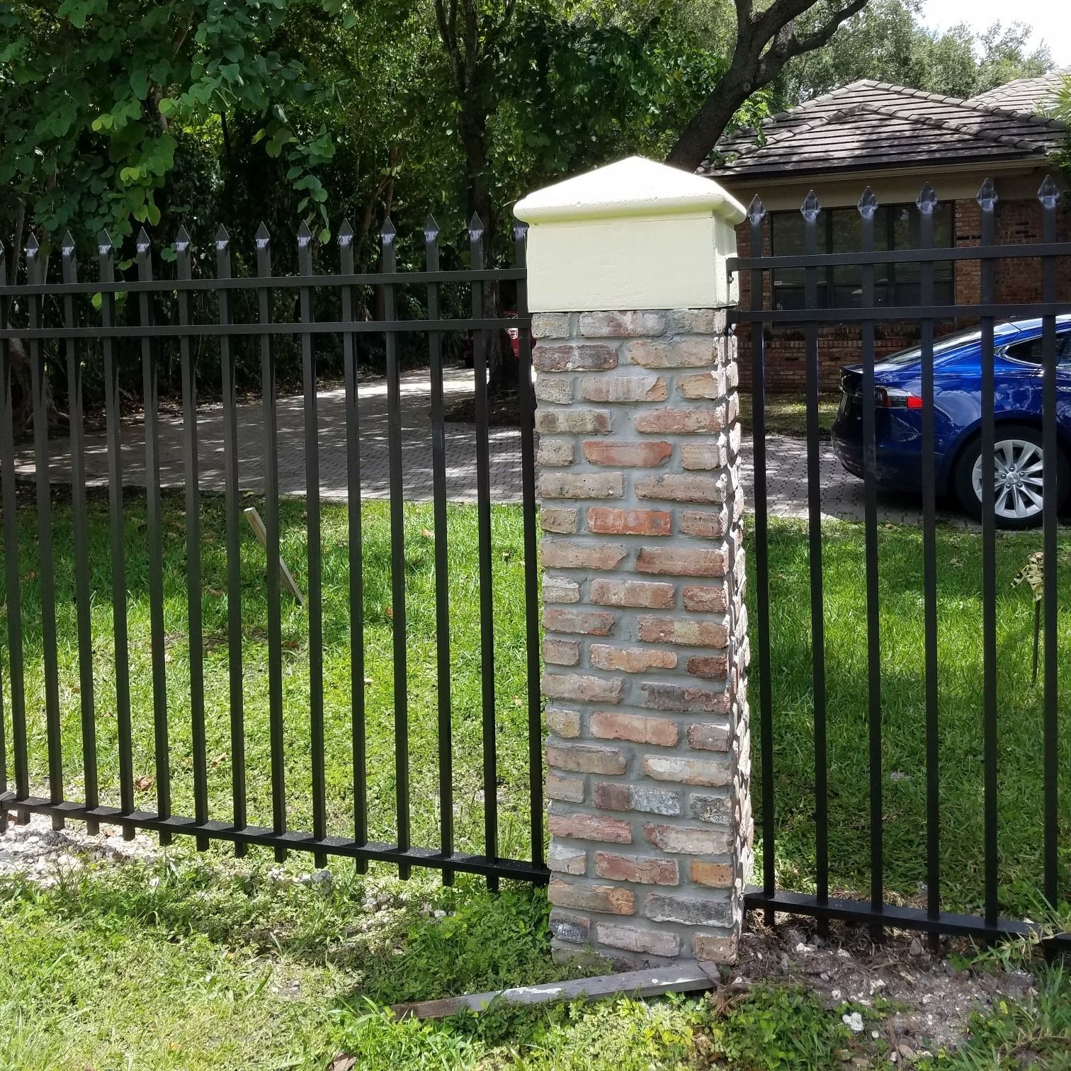 A black fence with a brick post in front of it
