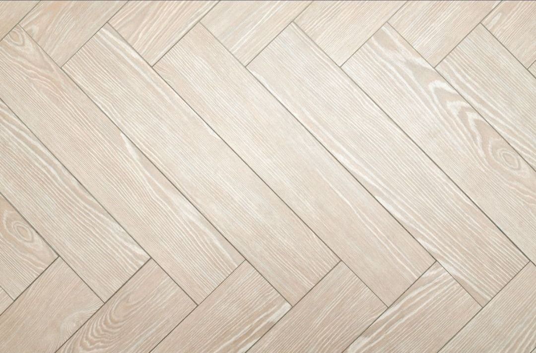 A close up of a wooden floor with a herringbone pattern.