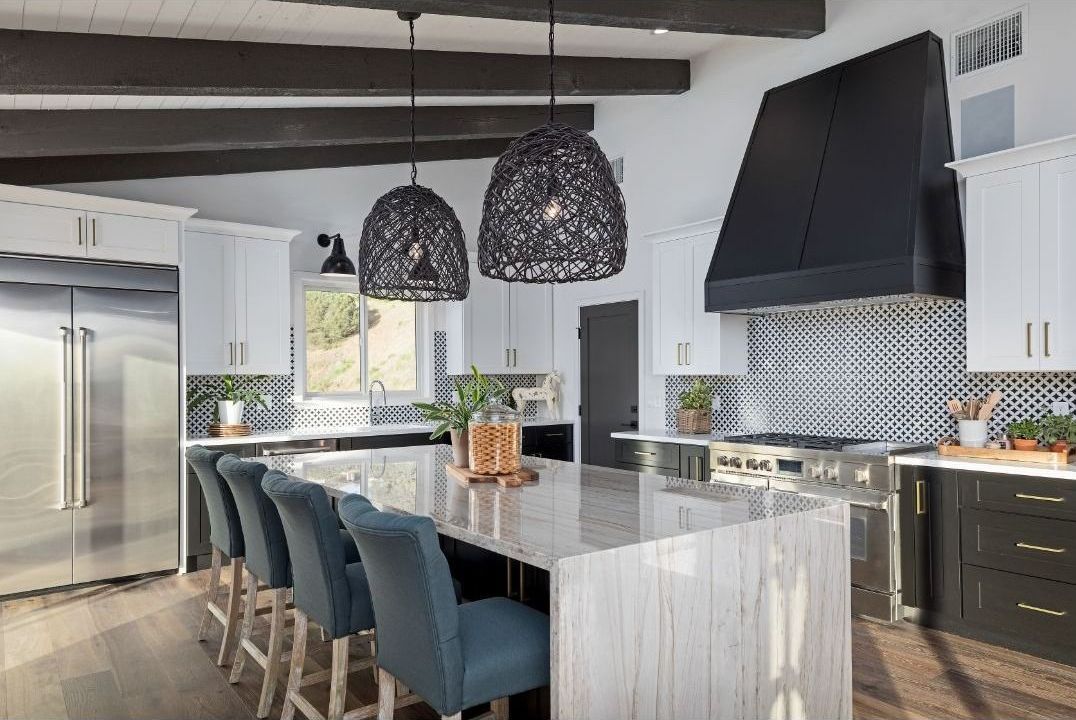 A kitchen with white cabinets , stainless steel appliances , and a large island.