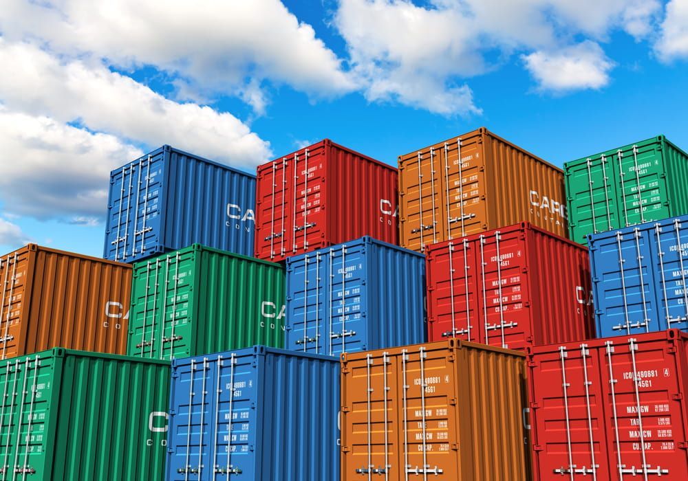 A Stack Of Colourful Shipping Containers Against A Blue Sky With Clouds — Newcastle Moving & Storage in Salt Ash, NSW
