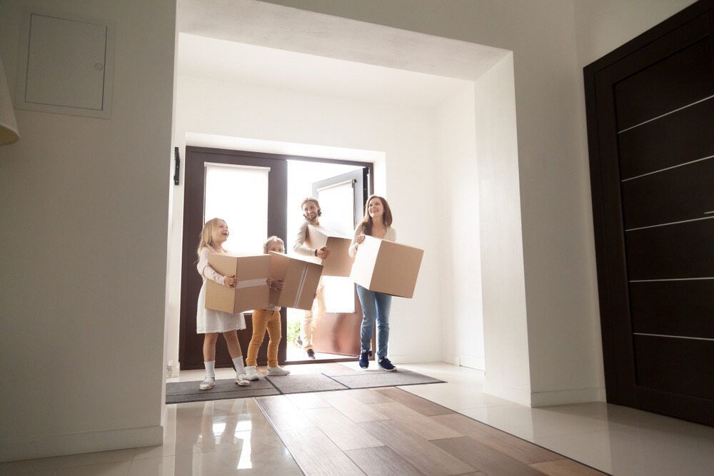 A Family Is Carrying Boxes Into A New Home — Newcastle Moving & Storage in Wyong, NSW